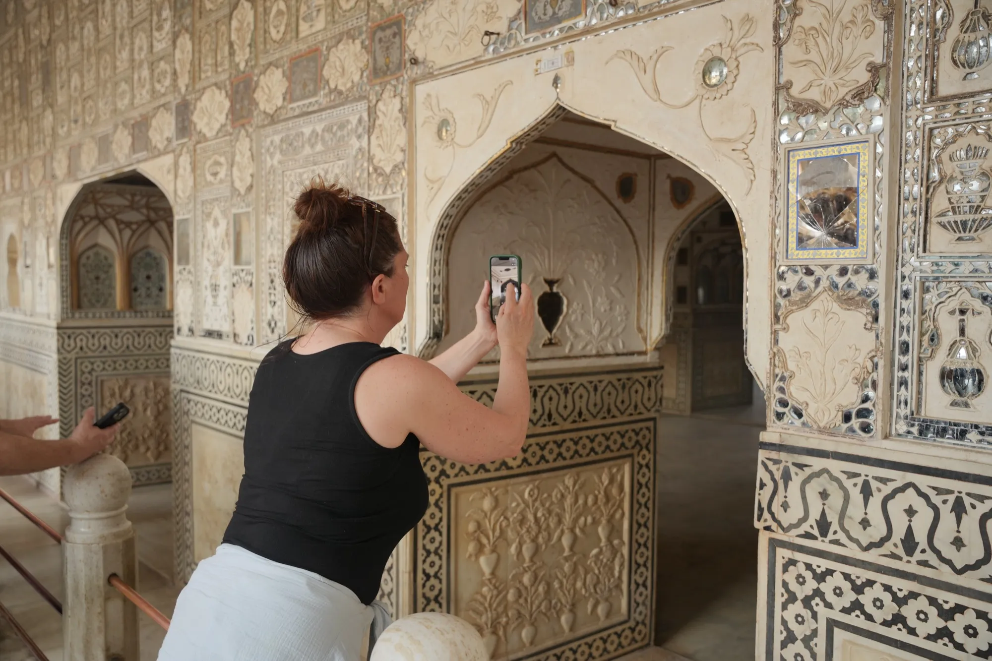 A guest photographing the mirror-work inside the Sheesh Mahal