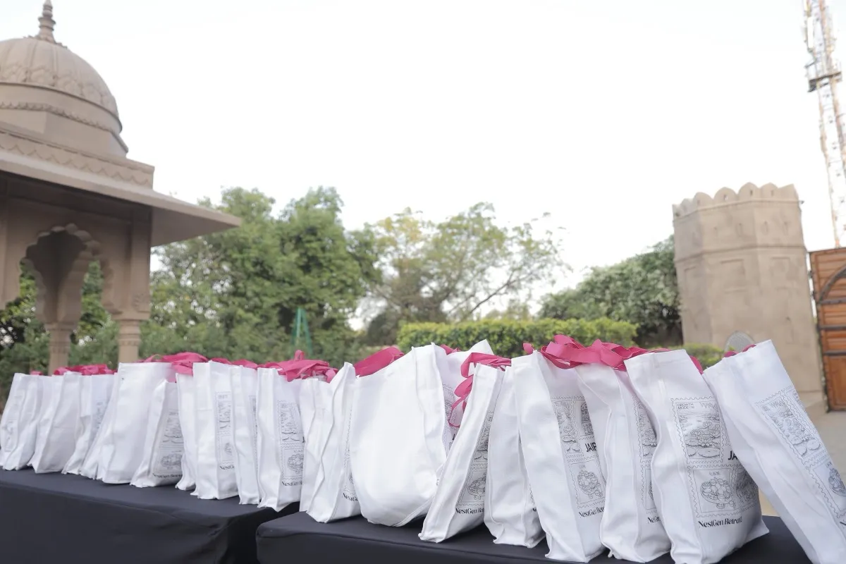 Rows of white NestGen tote bags laid out on a long table, the welcome gifts