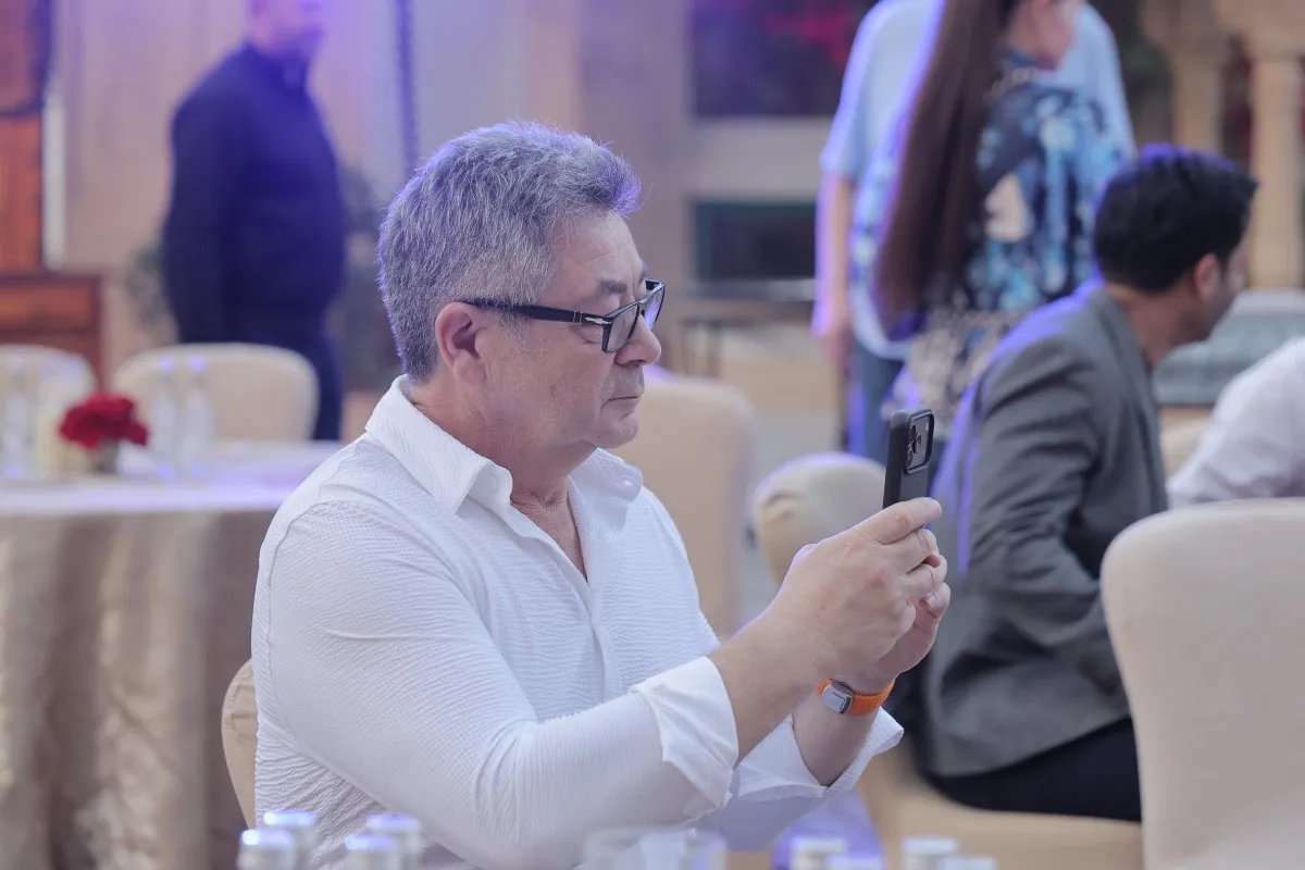 A guest at a dinner table filming the stage on a phone