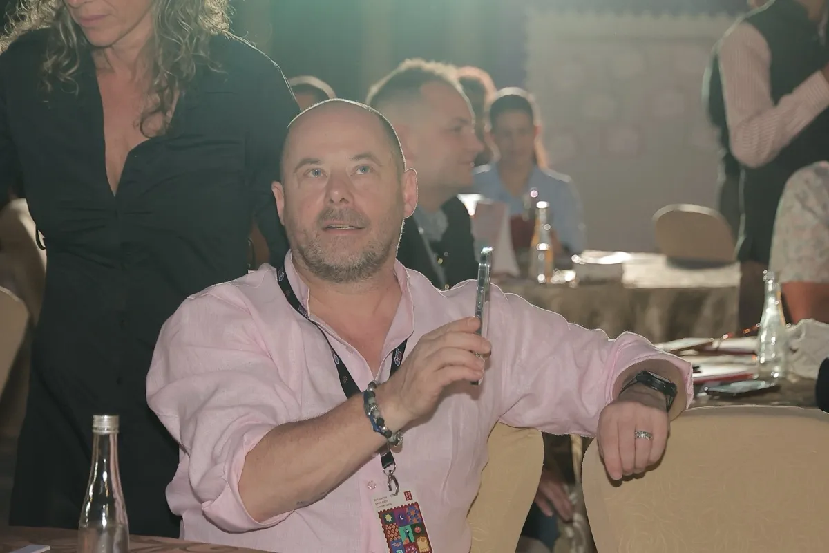 A guest in a pink shirt smiling at a dinner table at the Aagman evening