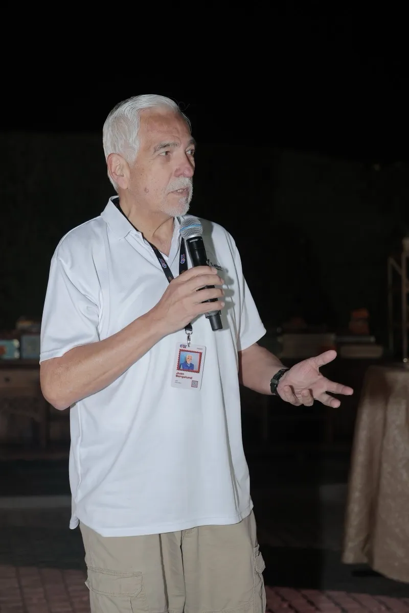 A guest in white speaking with a microphone at night