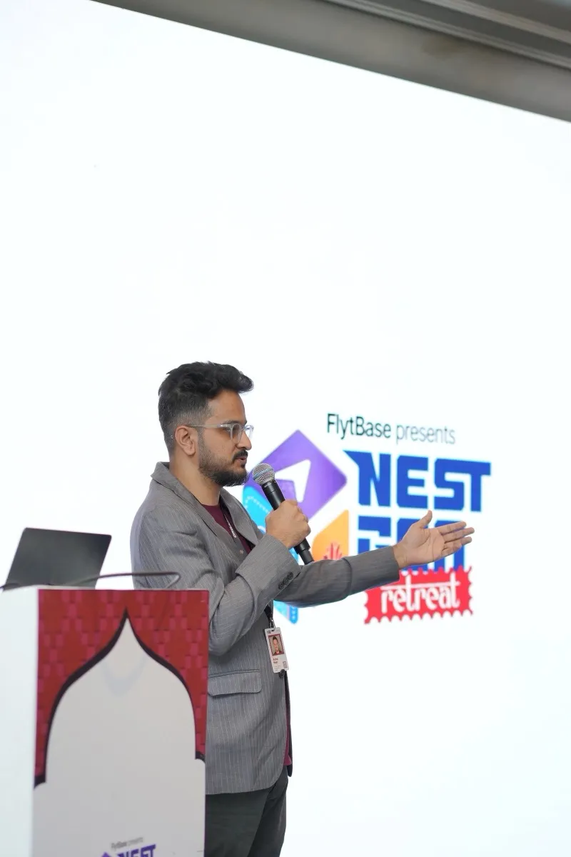 A speaker at the Forum lectern, in front of the NestGen Retreat screen
