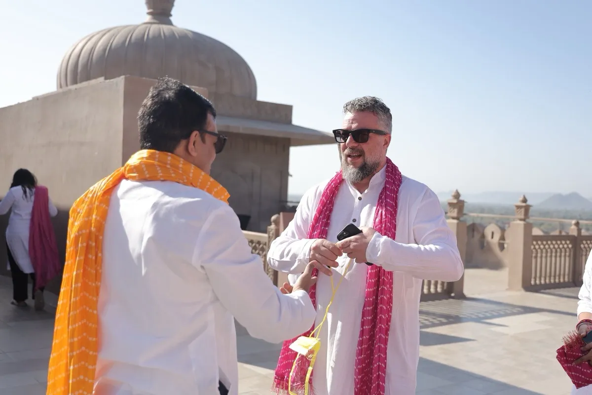 Two guests in white kurtas under a pavilion on the rooftop