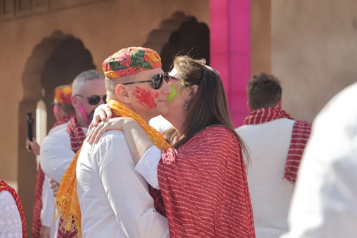 Two guests hugging, faces streaked with colour