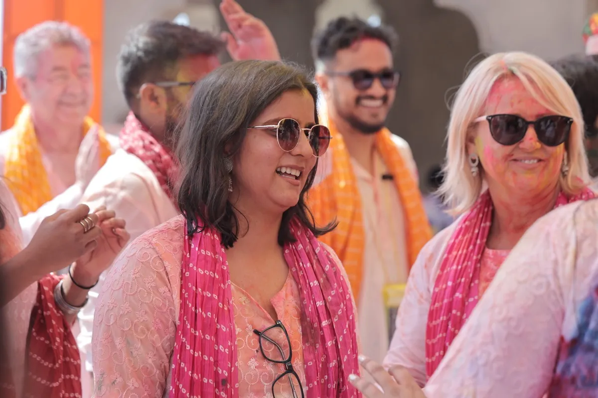 Three guests in sunglasses and pink dupattas, laughing together
