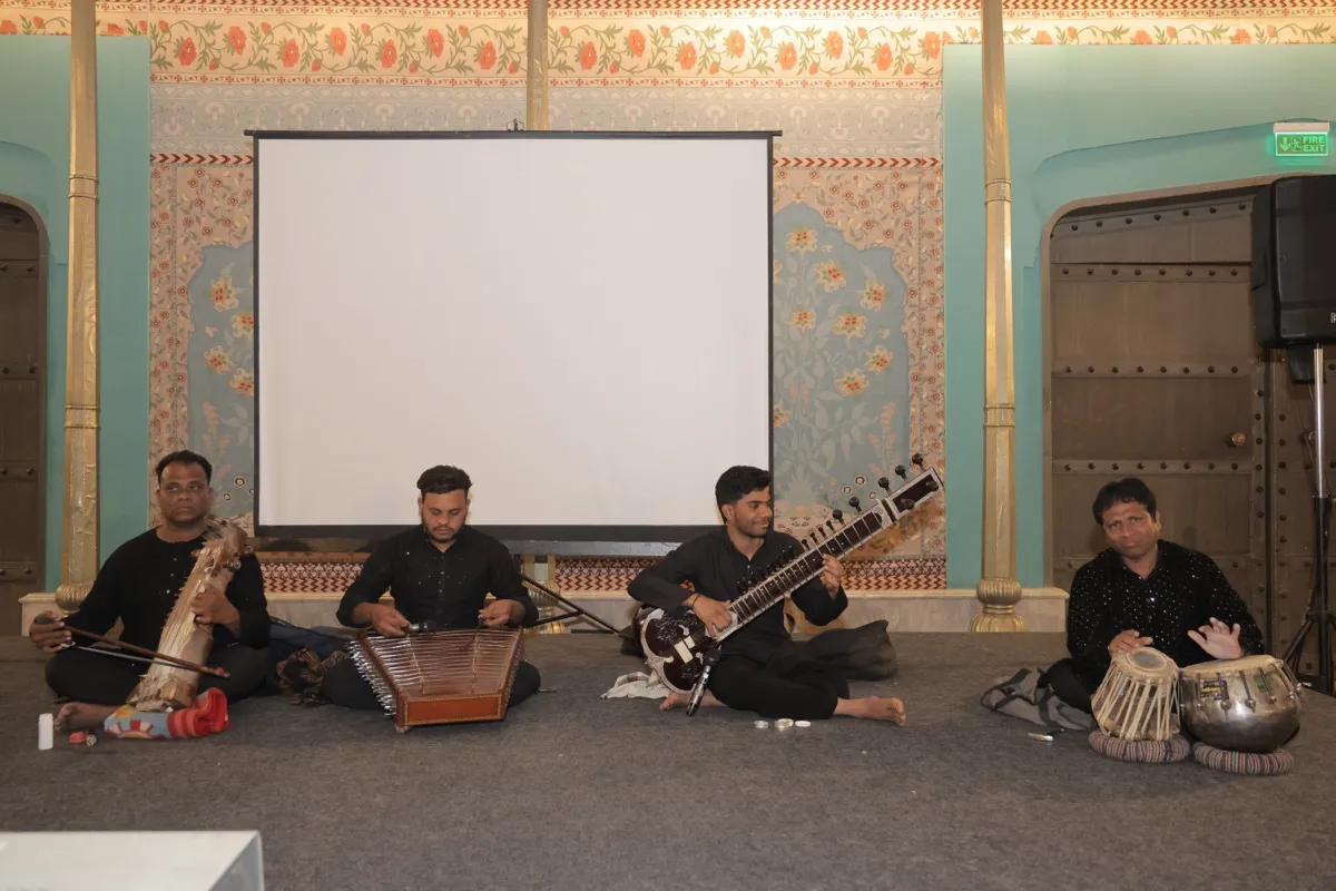 Four musicians on the floor with sitar, santoor, sarangi and tabla