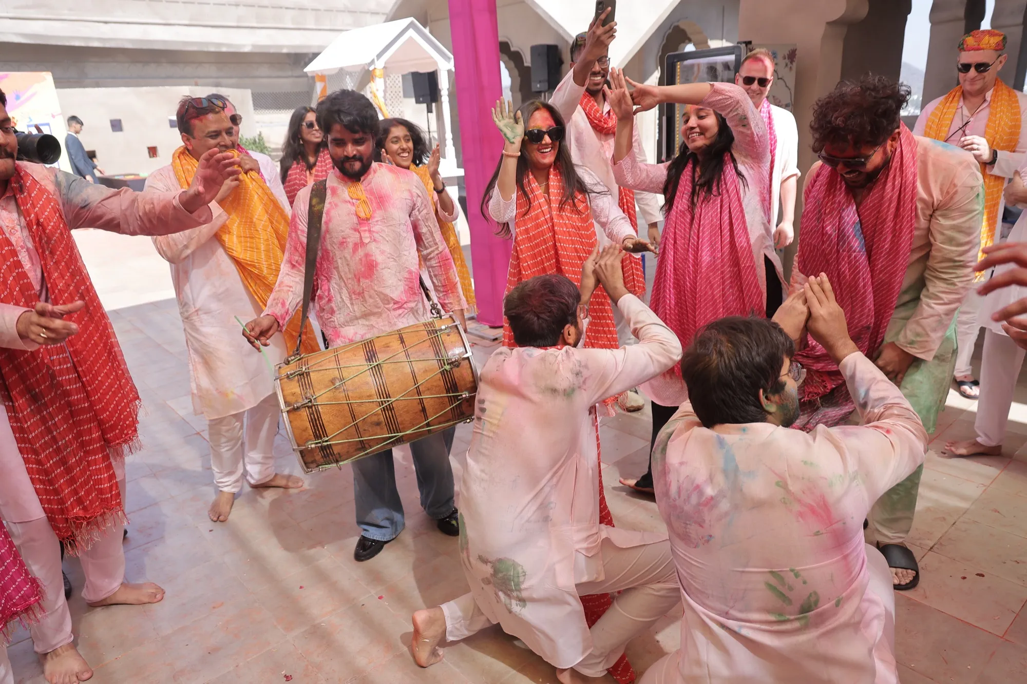 A dhol player in the middle of a dancing circle, guests clapping around him