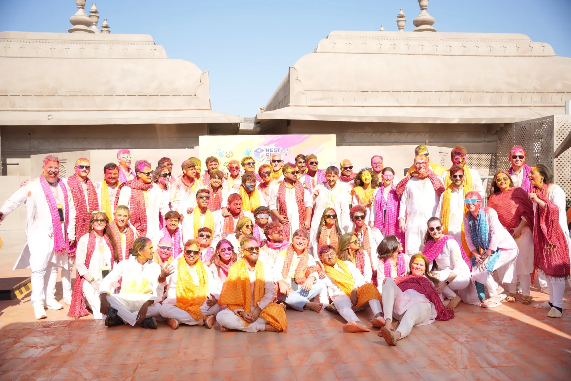 The whole group posed on the rooftop in white and pink, colour on every face