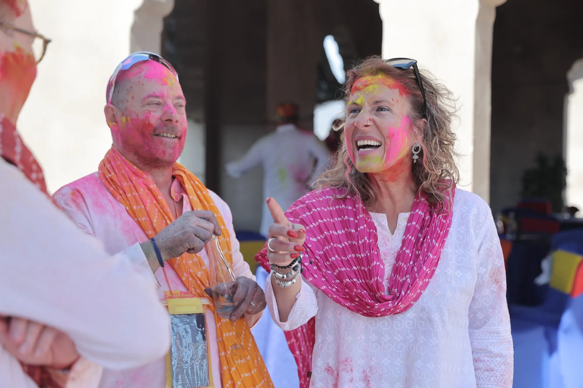 Two guests laughing, faces dusted yellow and pink