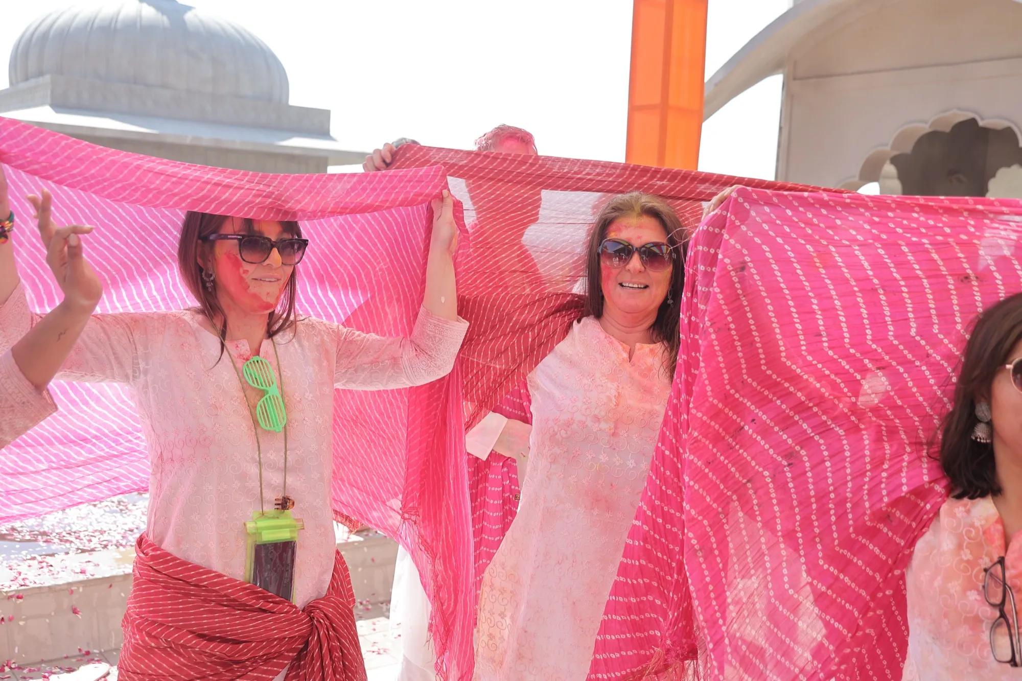 Guests holding pink dupattas high above their heads, dancing