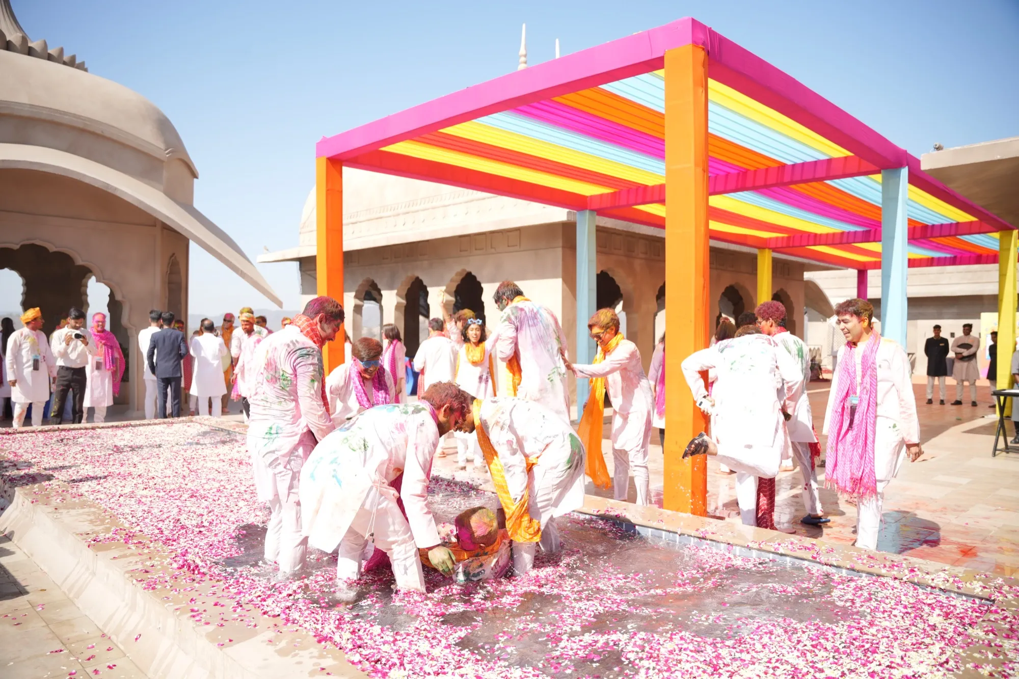 Guests dancing in a shallow pool of water and rose petals under the canopy