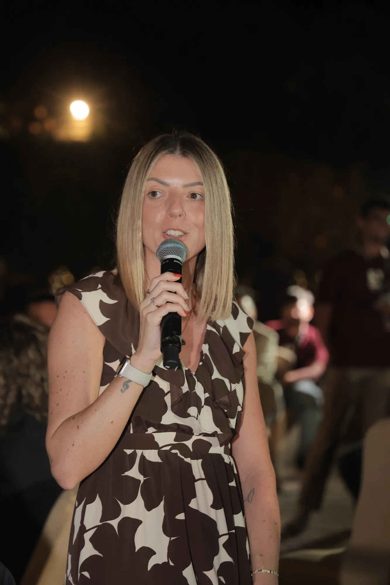 A guest introducing herself into a microphone at night