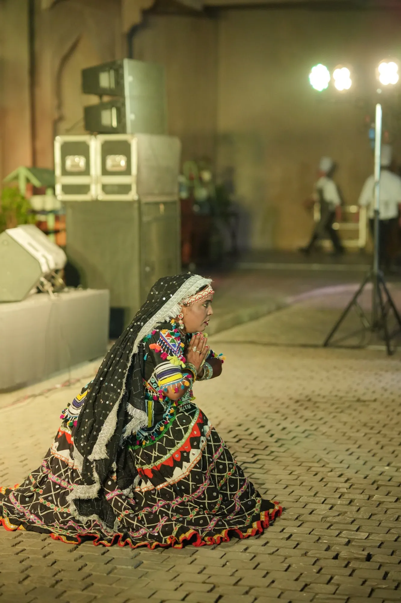 A Kalbeliya dancer crouched mid-spin on the courtyard stones