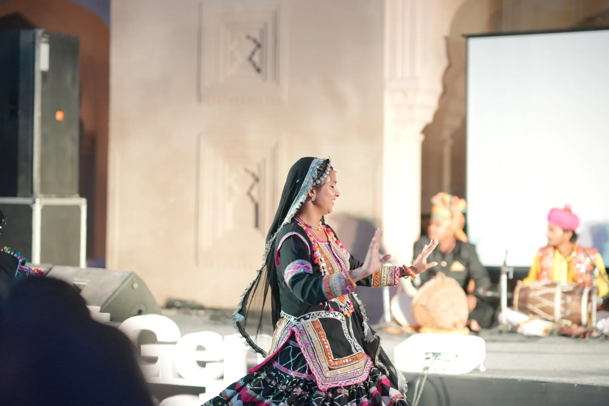 A Kalbeliya dancer in black and mirror-work spinning on the stage