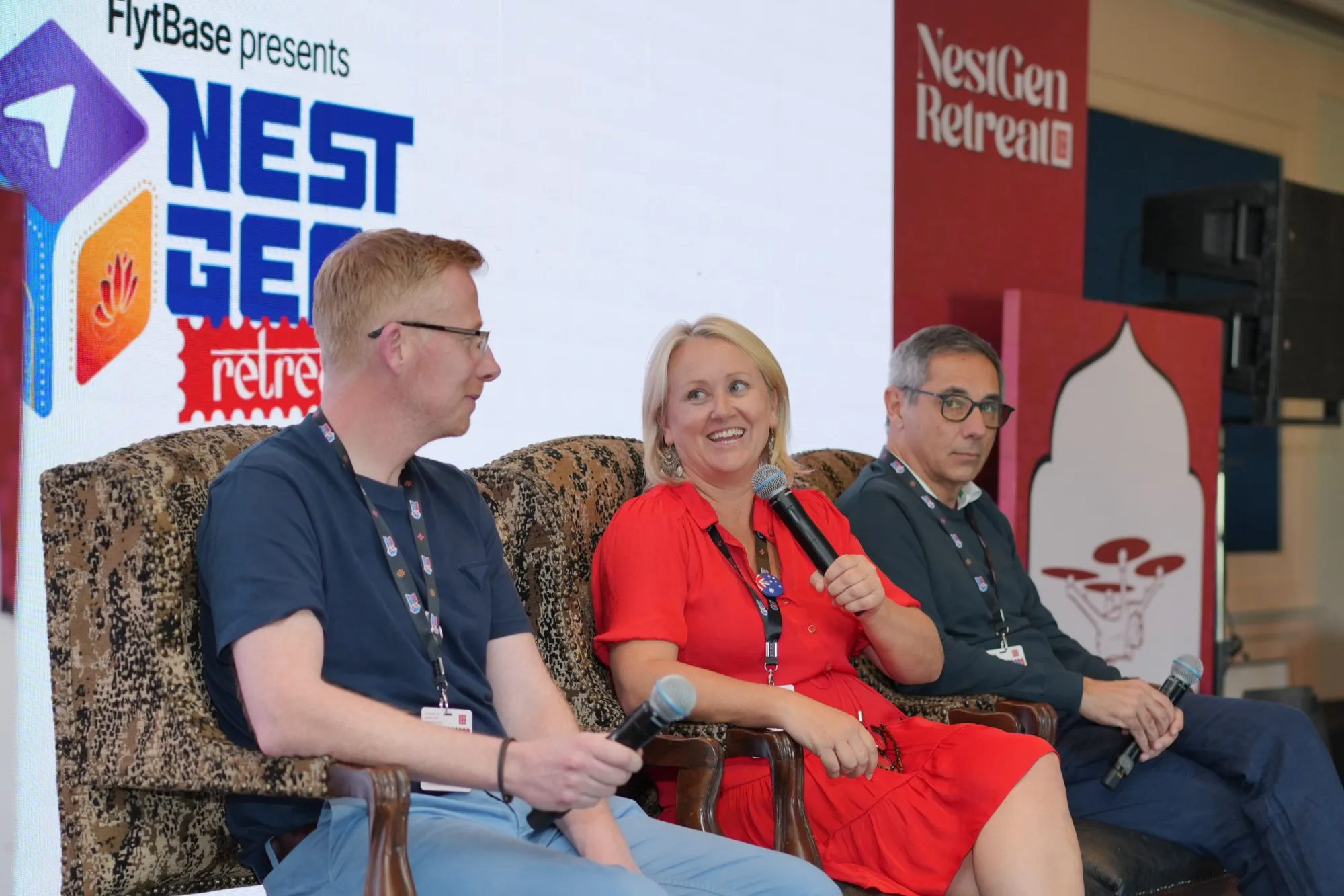 A panellist in red speaking into a microphone between two others