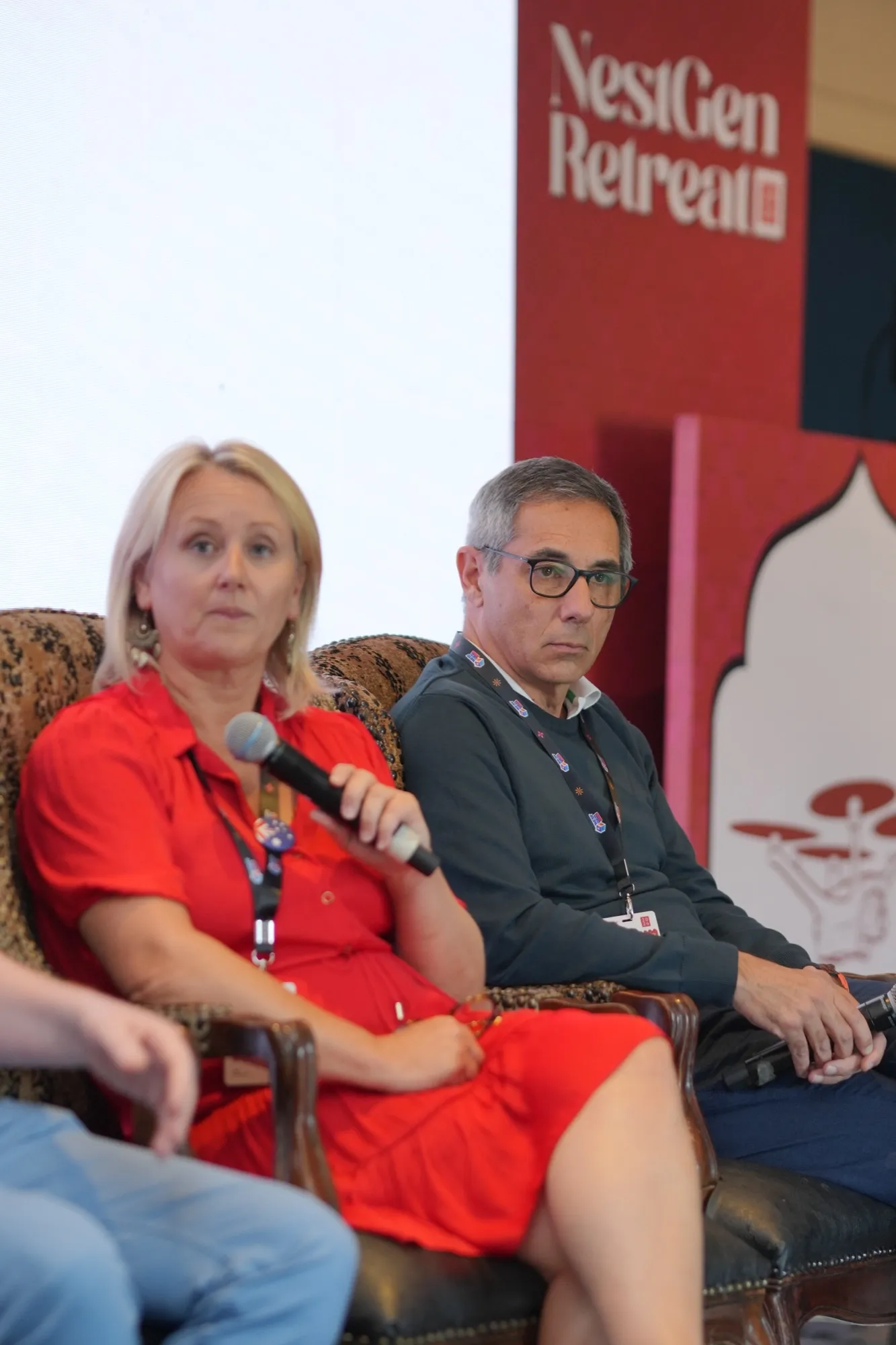 A panellist in red speaking into a microphone, a fellow panellist beside her