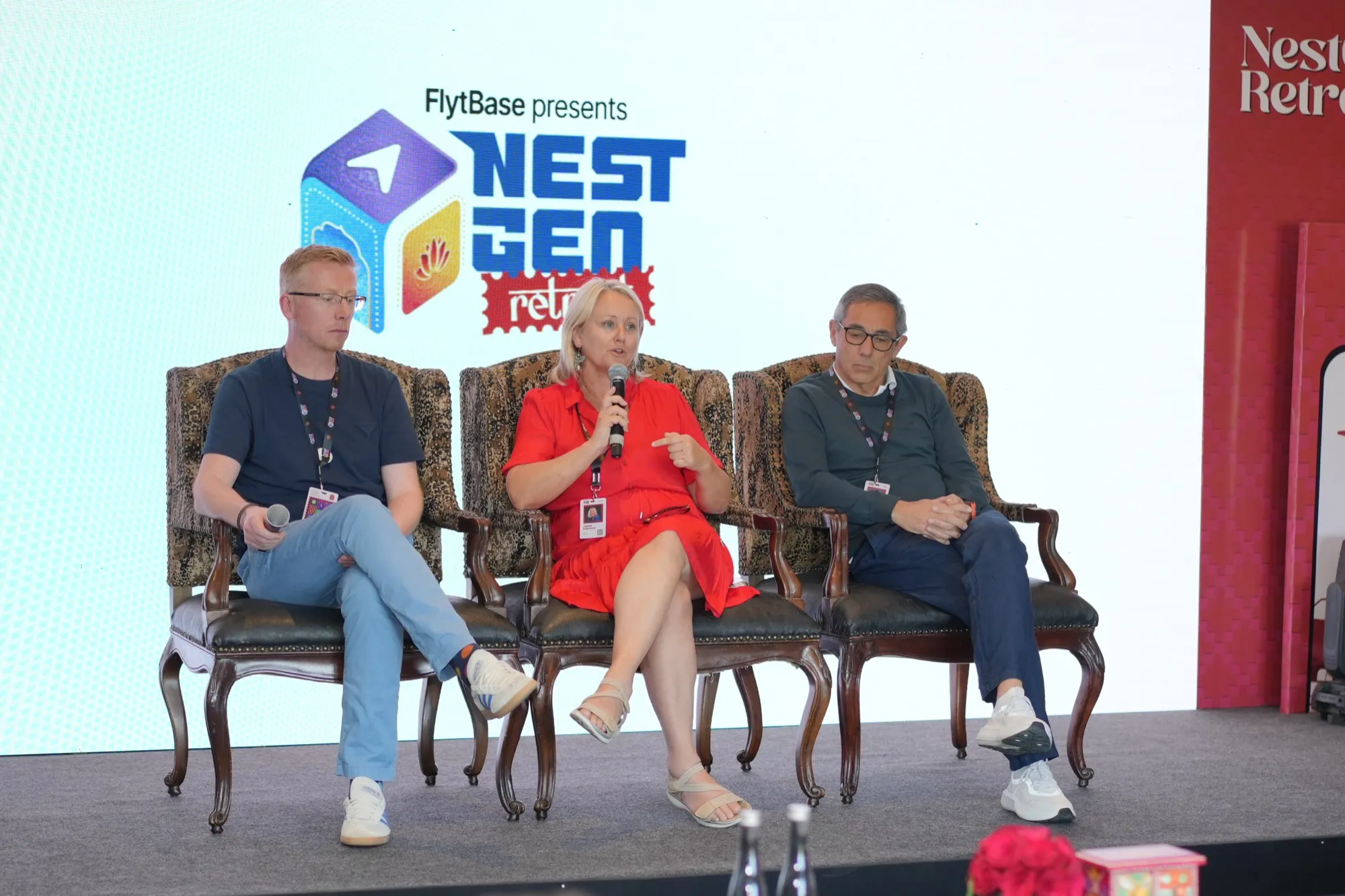 Three panellists in armchairs on the stage