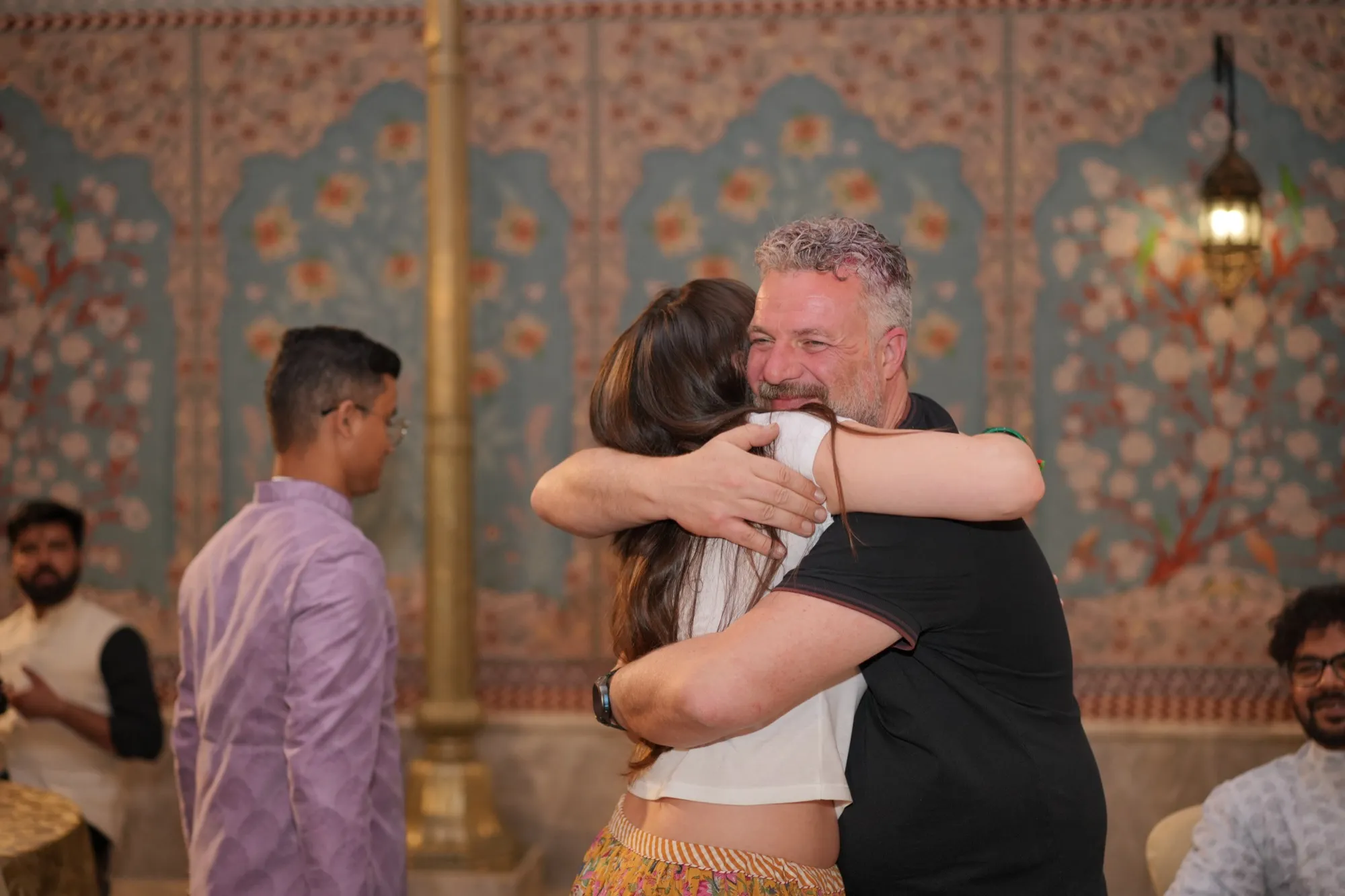 Two guests hugging goodbye in the painted hall