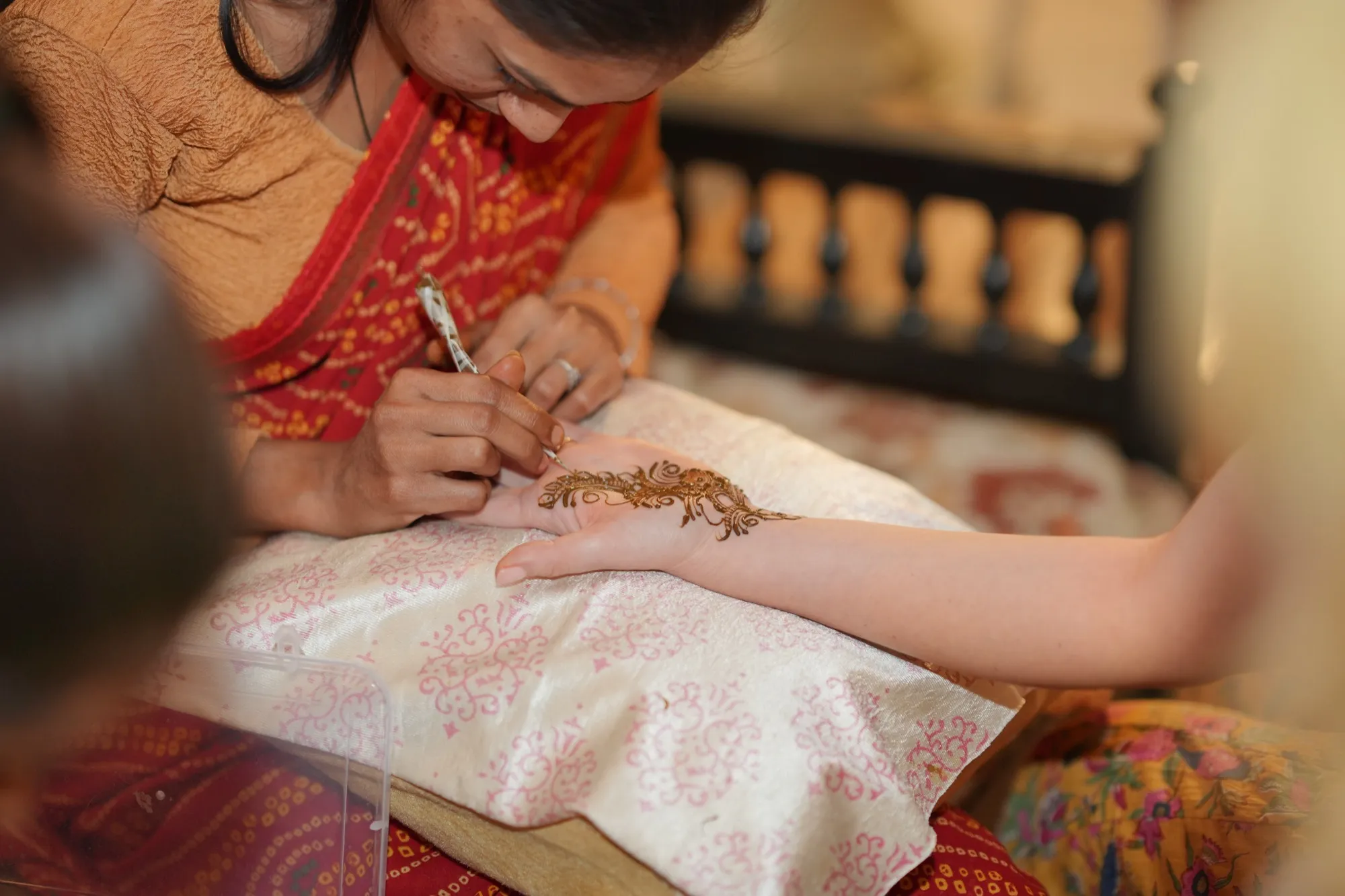 A close view of a henna cone tracing a pattern on a guest’s hand
