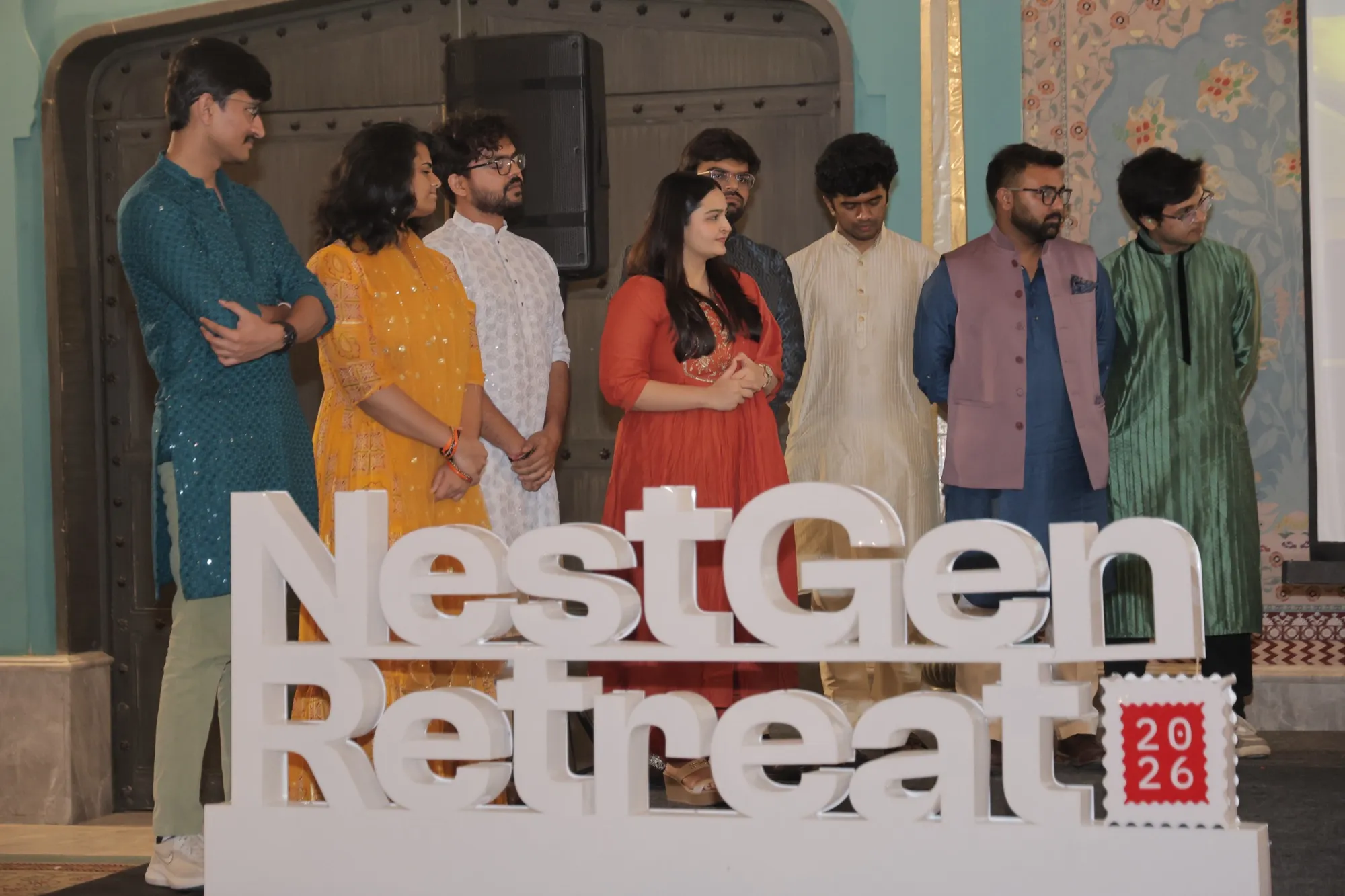 The FlytBase team standing on stage behind the NestGen Retreat sign
