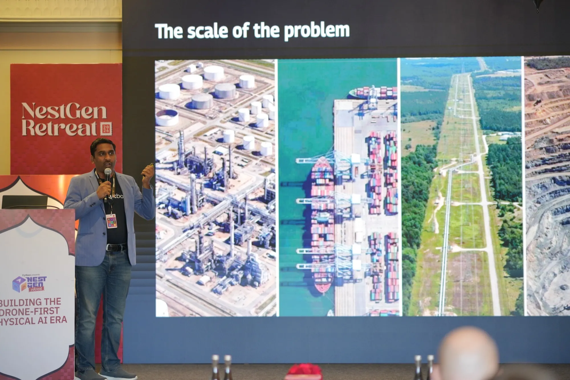 A speaker on stage beside a slide titled The scale of the problem