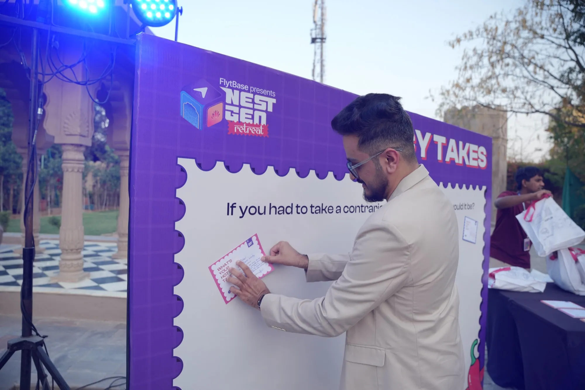 A guest in a cream jacket pinning his postcard to the Spicy Takes wall