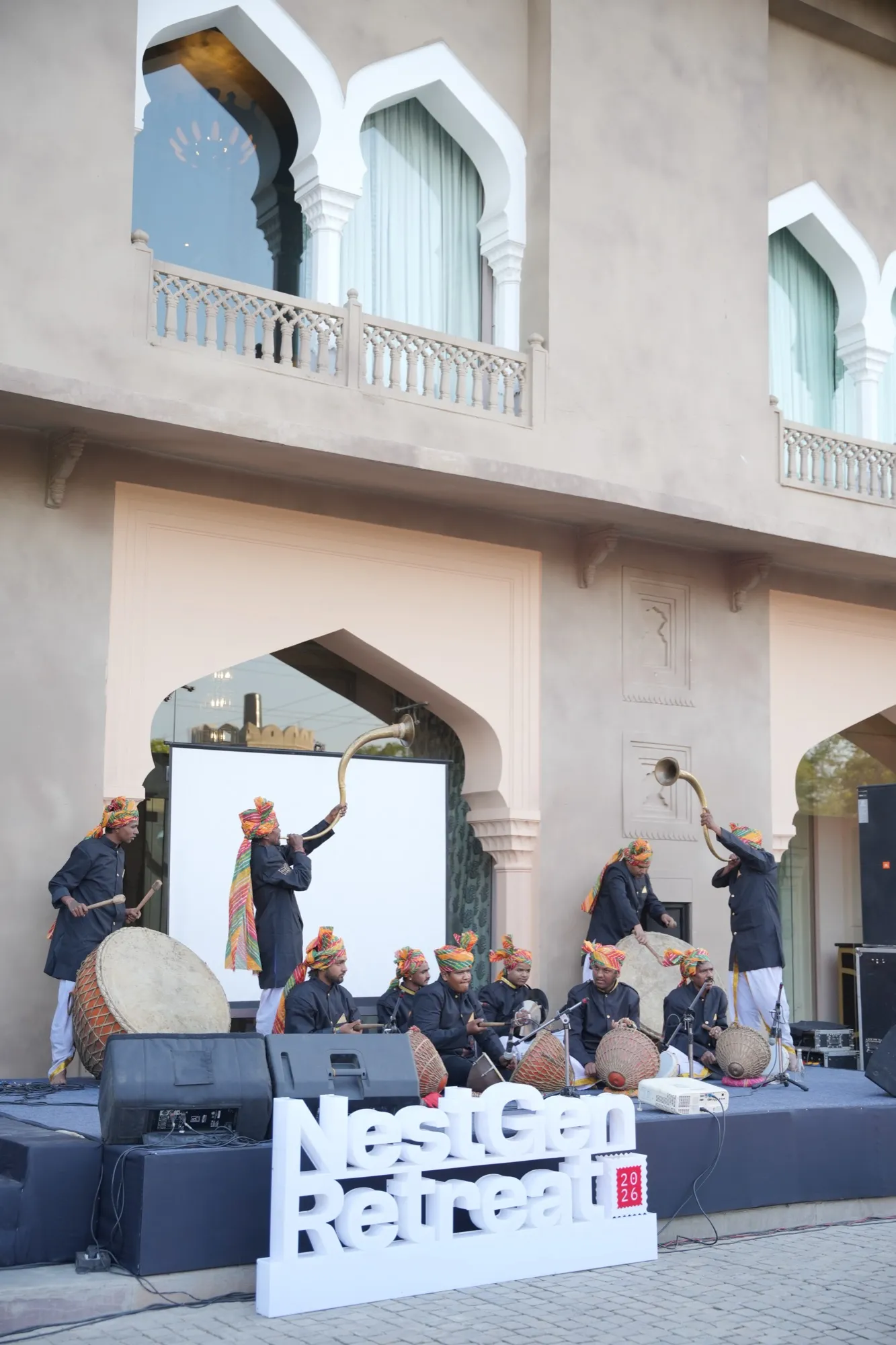 Musicians in turbans on the courtyard stage behind the NestGen Retreat sign