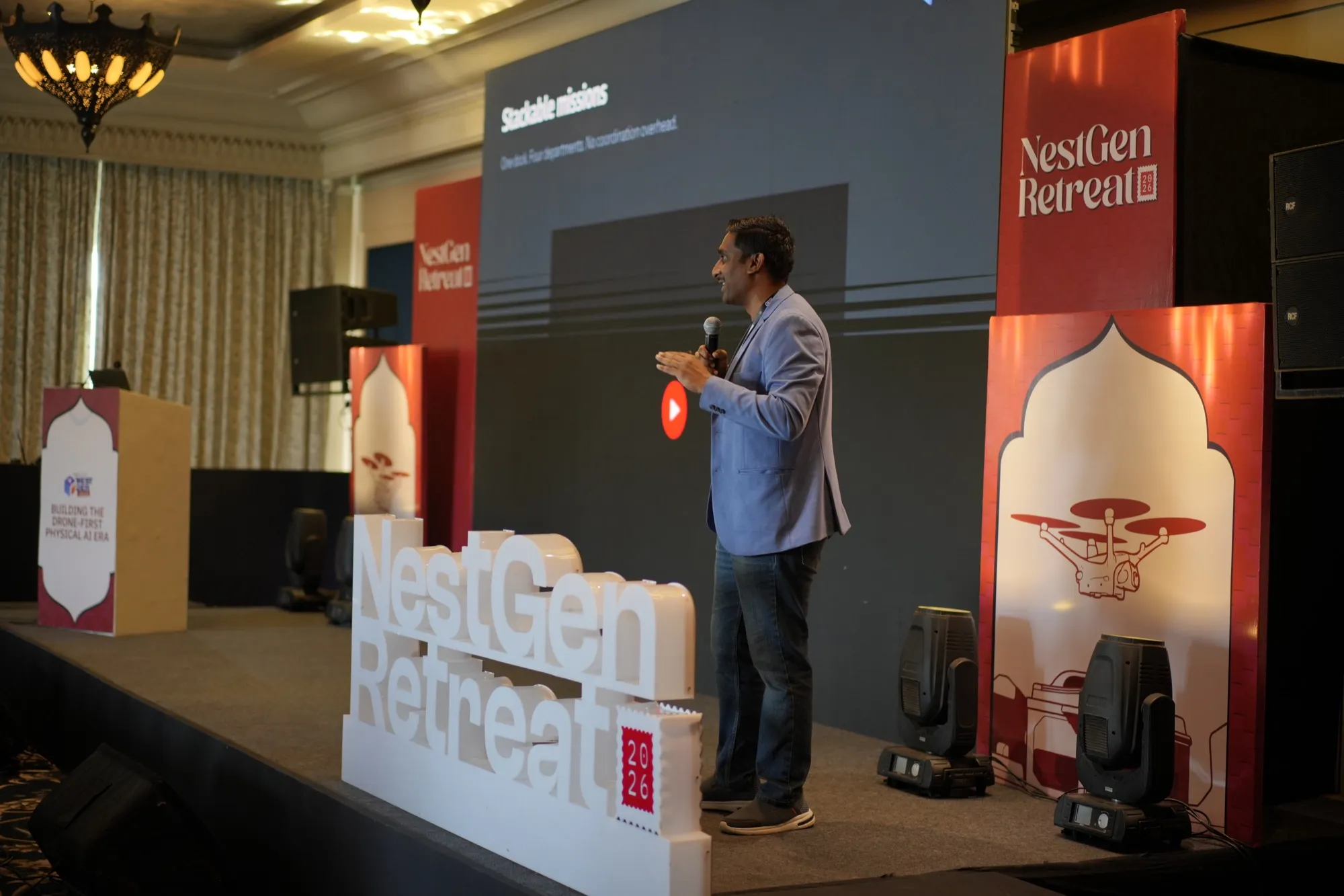 A speaker on the Forum stage beside the NestGen Retreat sign
