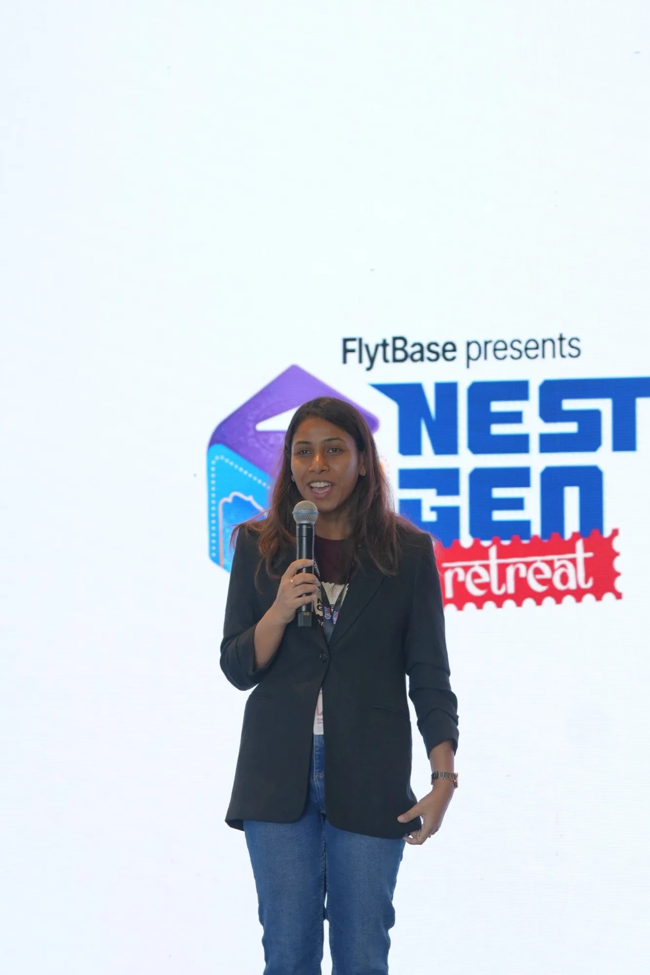 A speaker on stage against the white NestGen backdrop